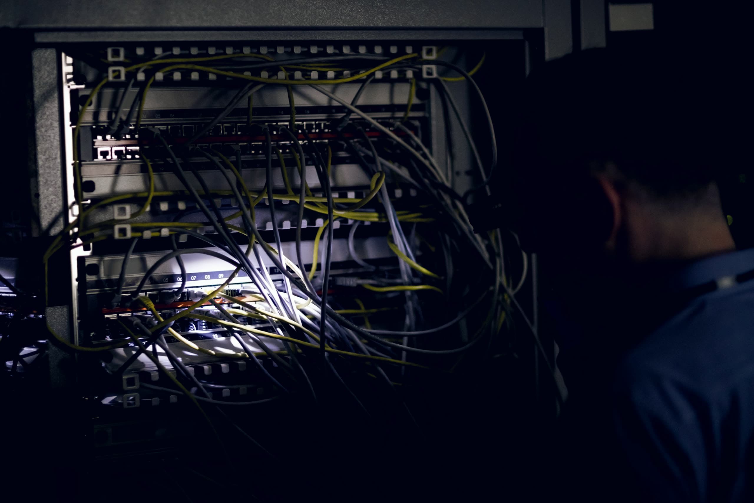 Técnico iluminando um rack de servidores com uma lanterna